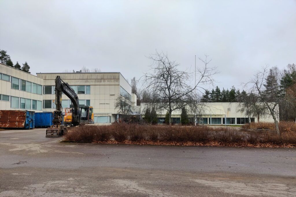 Koulurakennus, syksyinen ilma ja parkkipaikalla työkoneita.